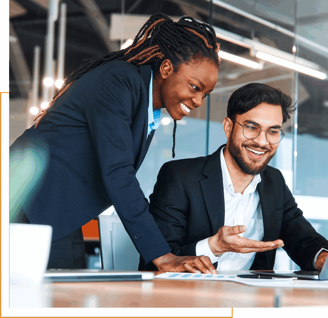 Two colleagues smiling at computer screen.